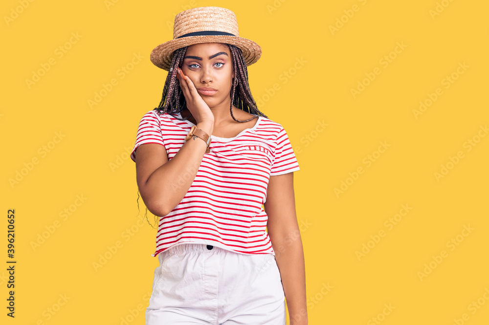 Young african american woman with braids wearing summer hat thinking looking tired and bored with depression problems with crossed arms. Young african american woman with braids wearing summer hat thinking looking tired and bored with depression problems with crossed arms.