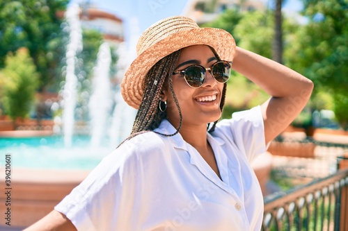 Fotografie Young african american woman with braids wearing sunglasses and smiling happy ou