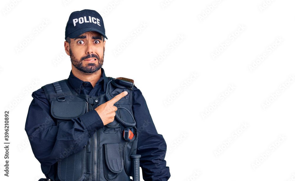 Young hispanic man wearing police uniform pointing aside worried and nervous with forefinger, concerned and surprised expression Young hispanic man wearing police uniform pointing aside worried and nervous with forefinger, concerned and surprised expression