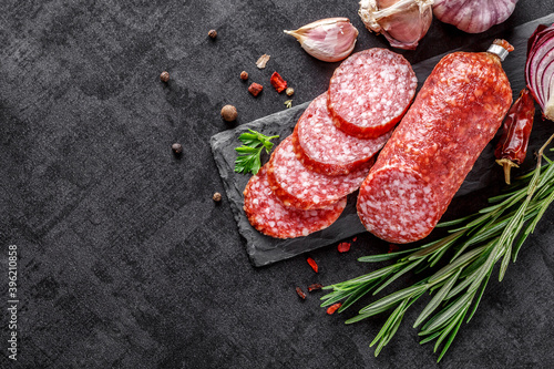 Traditional smoked salami sausage with spices.Salami sausage slices on a black chopping Board. Dark background. photo