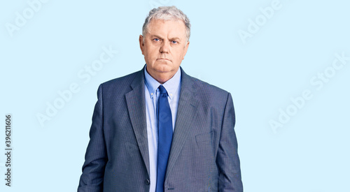 Senior grey-haired man wearing business jacket relaxed with serious expression on face. simple and natural looking at the camera.