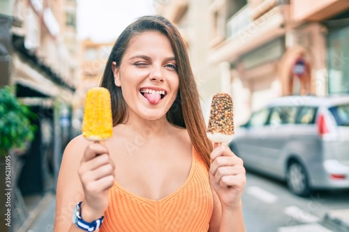Young middle east girl bitting tongue and winking holding ice cream at the city.