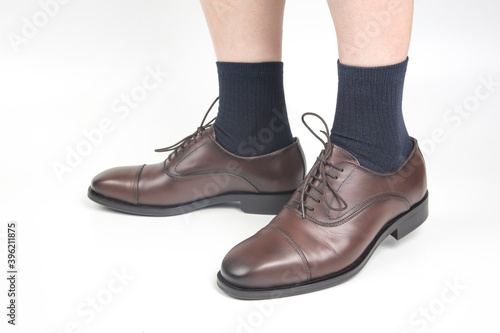 Male legs in socks and brown classic shoes on a white background