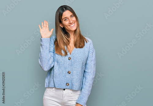 Young woman wearing casual clothes waiving saying hello happy and smiling, friendly welcome gesture