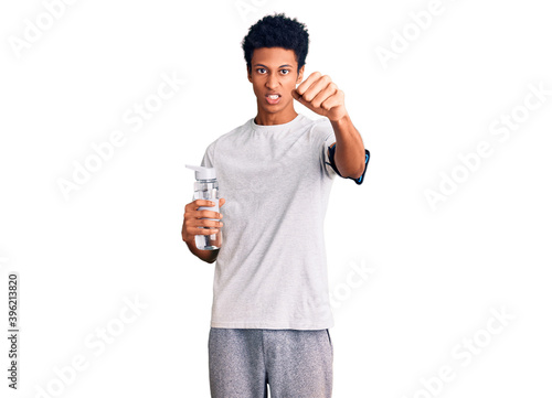 Young african american man wearing sportswear holding water bottle annoyed and frustrated shouting with anger  yelling crazy with anger and hand raised