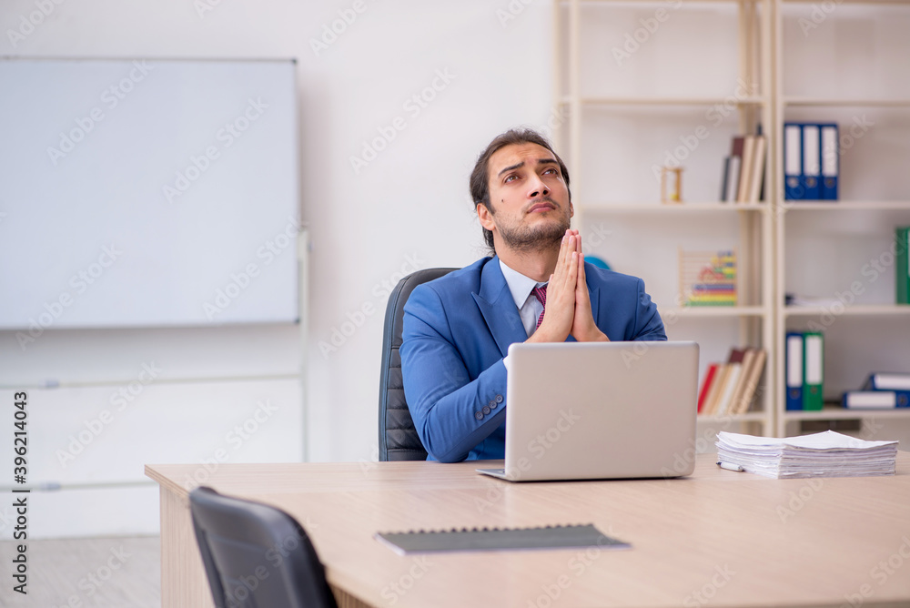 Young male employee sitting in the office in front of whiteboard Young male employee sitting in the office in front of whiteboard