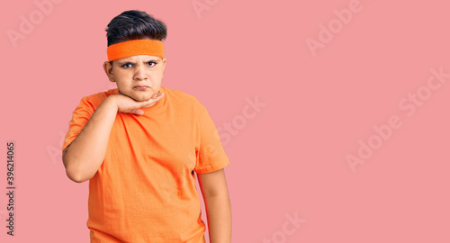 Little boy kid wearing sportswear cutting throat with hand as knife, threaten aggression with furious violence