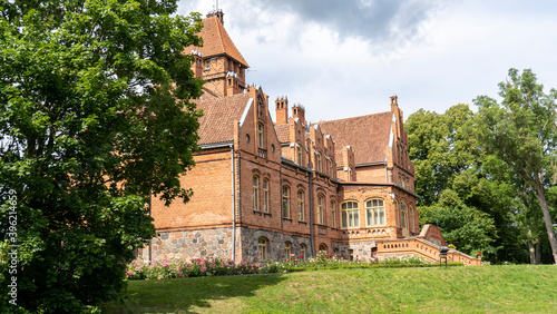 Tume, Latvia_- July 7, 2020: Brick Medieval Jaunmoku Castle at Pond. The Jaunmokas Manor Park. This Neo-gothic Palace Was Designed by Architect Wilhelm Bockslaff and Built in 1901.