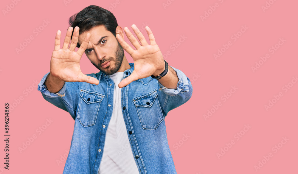 Young hispanic man wearing casual clothes doing frame using hands palms and fingers, camera perspective Young hispanic man wearing casual clothes doing frame using hands palms and fingers, camera perspective