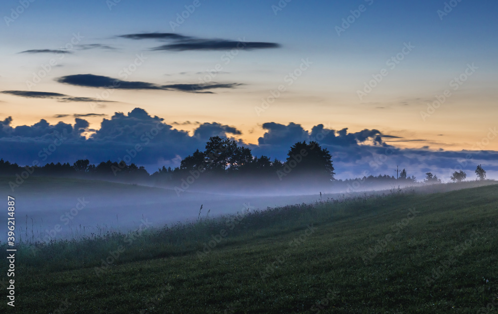 Fog rising over fields near Jeziorowskie village, Masuria region of Poland