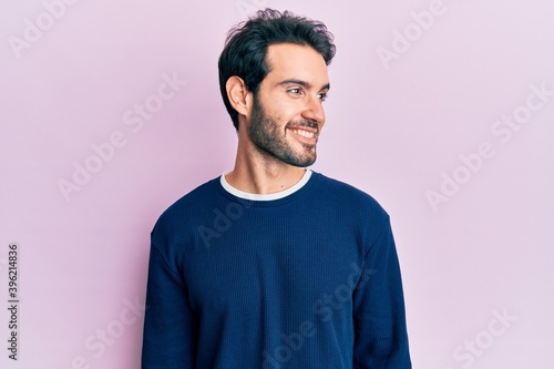 Young hispanic man wearing casual clothes looking to side, relax profile pose with natural face and confident smile.