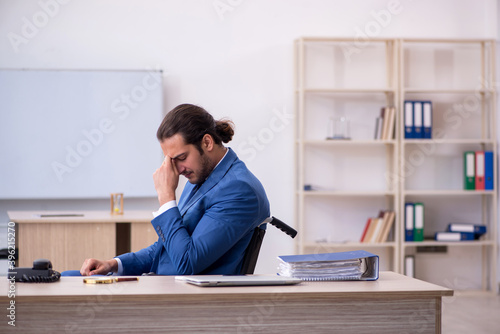 Young male employee in wheel-chair working in the office