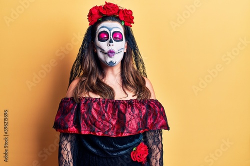 Young woman wearing day of the dead costume over yellow making fish face with lips, crazy and comical gesture. funny expression.