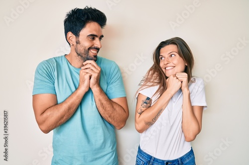 Beautiful young couple of boyfriend and girlfriend together laughing nervous and excited with hands on chin looking to the side