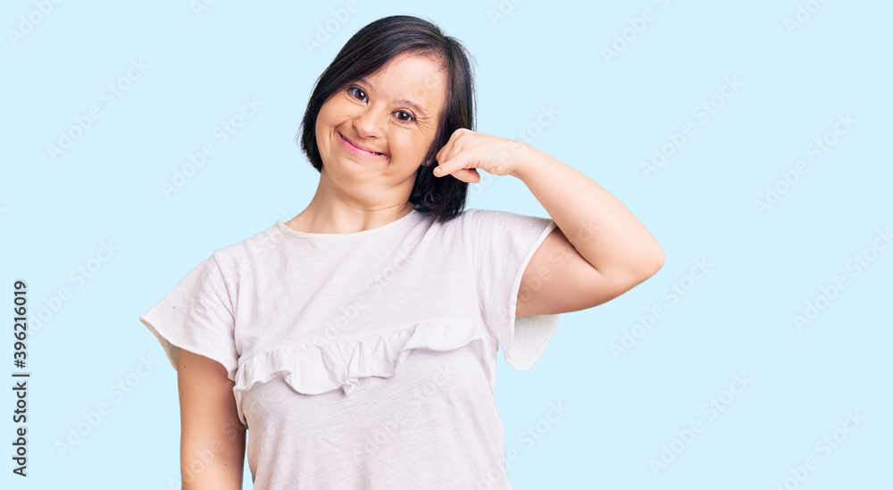 Brunette woman with down syndrome wearing casual white tshirt smiling doing phone gesture with hand and fingers like talking on the telephone. communicating concepts. Brunette woman with down syndrome wearing casual white tshirt smiling doing phone gesture with hand and fingers like talking on the telephone. communicating concepts.