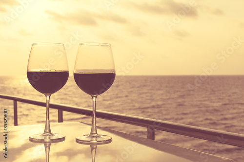 Glasses, red wine and tropical sunset with sea background, nobody.