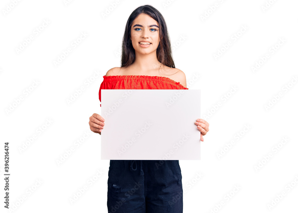 Brunette teenager girl holding blank empty banner looking positive and happy standing and smiling with a confident smile showing teeth Brunette teenager girl holding blank empty banner looking positive and happy standing and smiling with a confident smile showing teeth