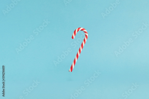 Christmas red flying candy cane on blue background. Merry Christmas levitation sweets and Happy New Year concept