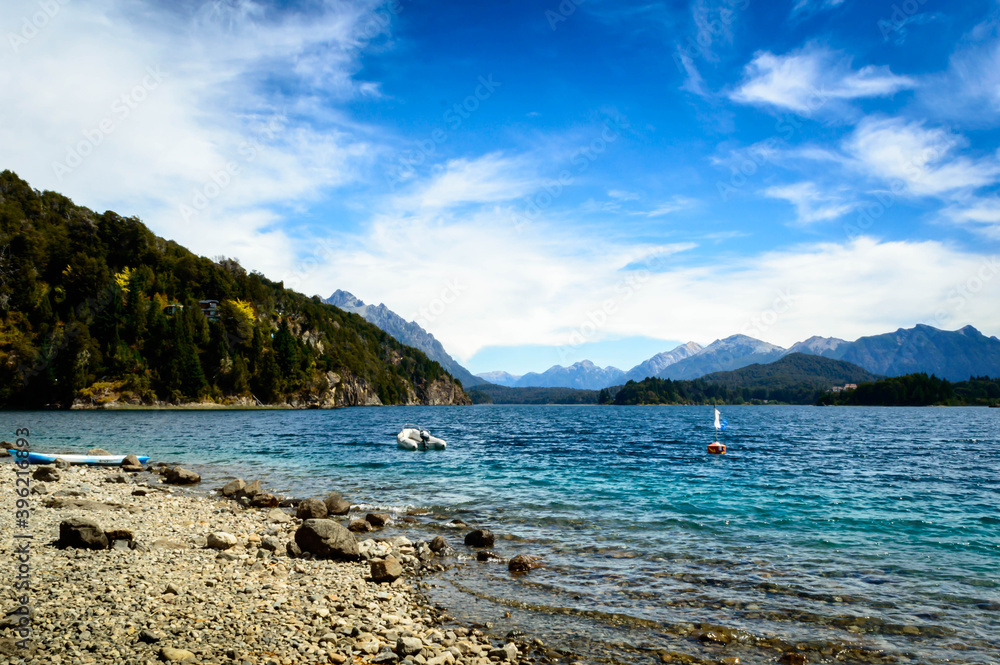 Beautiful lake landscape between the mountains and a boat. Very sunny day between rocks, pine trees and mountains