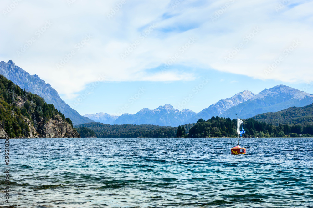 Buoy in the crystal clear lake. Mountains and pine trees in the background. Hot day in Bariloche