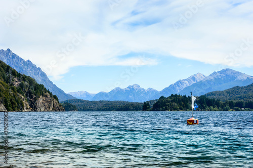 Buoy in the crystal clear lake. Mountains and pine trees in the background. Hot day in Bariloche