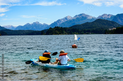 A couple paddling on a lake in Bariloche. Rocks, pines and mountains. Summer day © Rariel