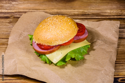 Fresh hamburger on brown paper on wooden table