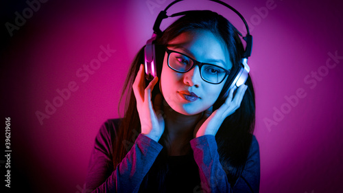 Young Asian woman listens to music - strong colorful shot - home shooting