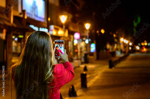 Woman with a red jacket taking a selfie in the center of Bariloche.