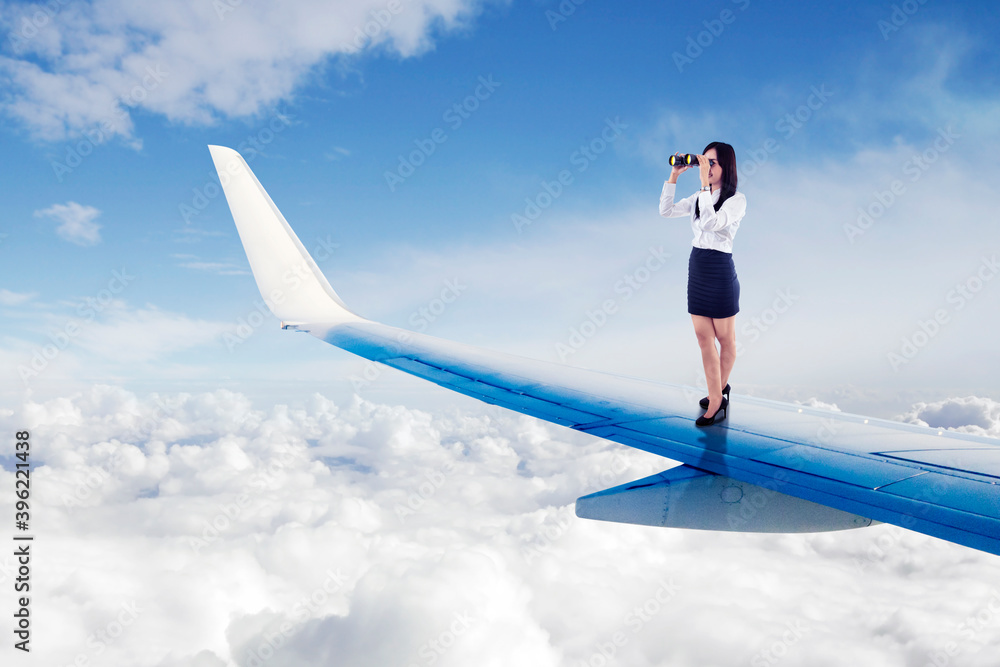 Businesswoman using binoculars on airplane wings Businesswoman using binoculars on airplane wings