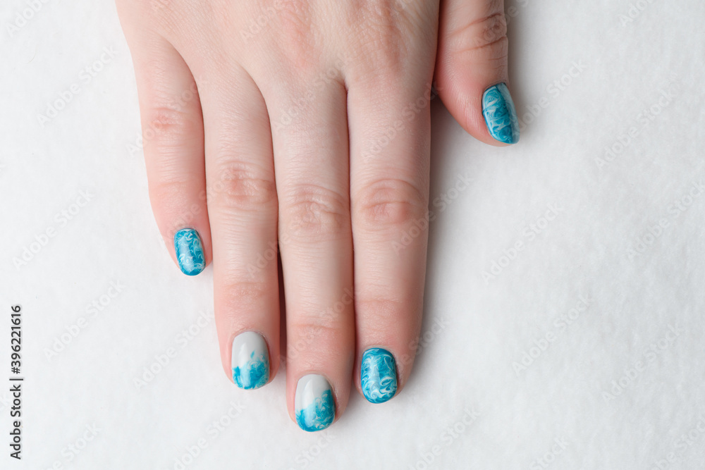 Manicure gel lacquer sea wave color with light gray on white background Manicure gel lacquer sea wave color with light gray on white background