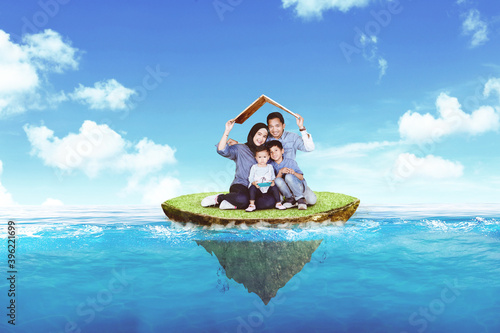 Family hold a house roof on floating island in sea