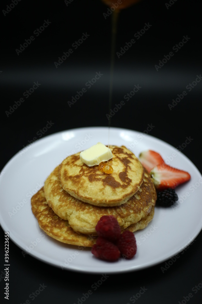 Pancakes stack with different berries and honey isolated on black background Pancakes stack with different berries and honey isolated on black background