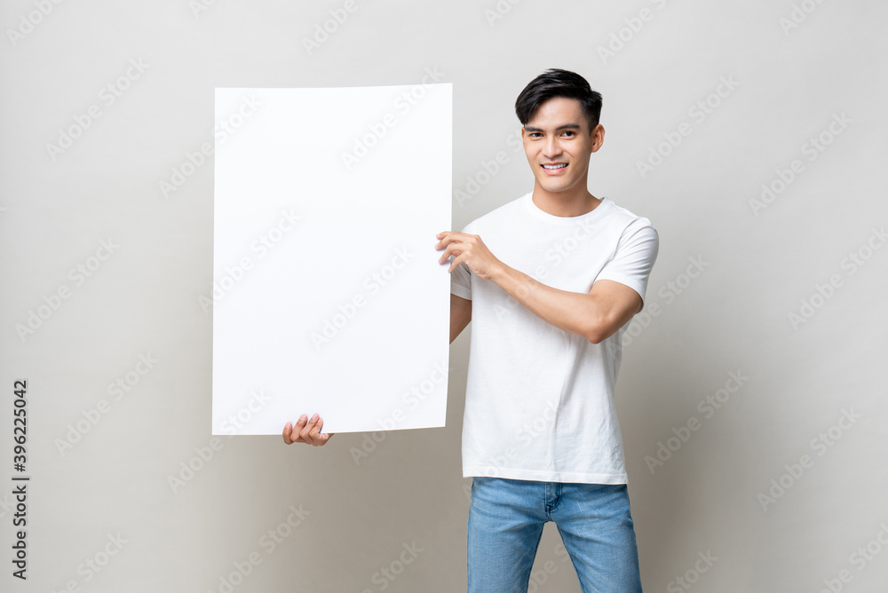 Portrait of handsome Asian man holding empty white placard in isolated studio gray background Portrait of handsome Asian man holding empty white placard in isolated studio gray background