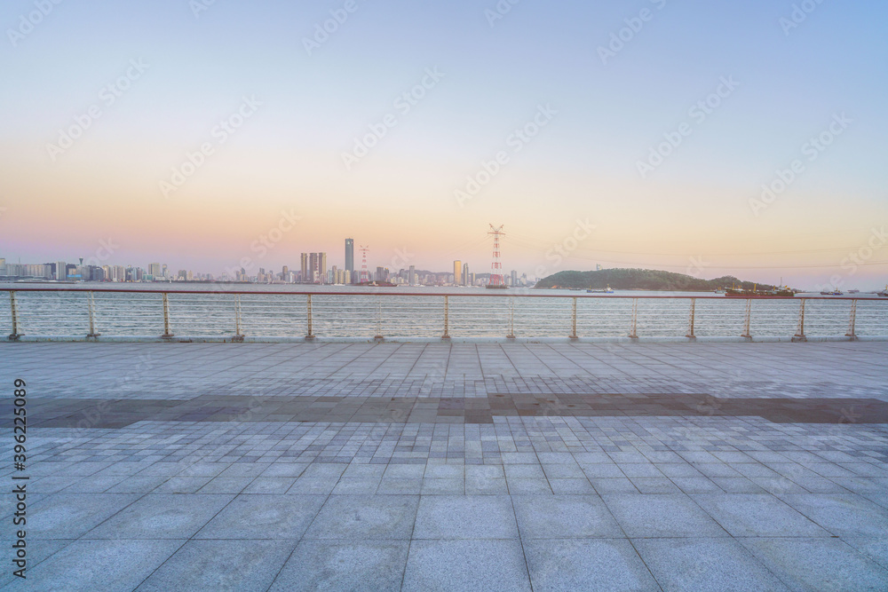 Sunrise landscapes at the coastline of Xiamen island with empty square at foreground and modern skyline at background