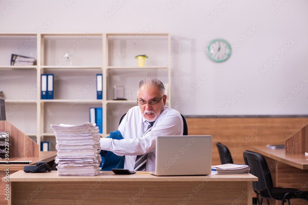 Old male employee unhappy with excessive work in the office Old male employee unhappy with excessive work in the office