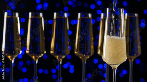 A filling glass of sparkling wine against the background of a row of full glasses.