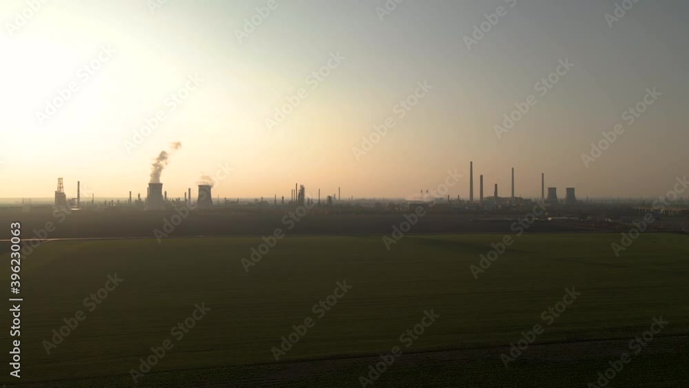 Aerial wide shot of rural farm field and Oil Refinery Near Ploiesti City in background.Beautiful sunset at horizon. Aerial wide shot of rural farm field and Oil Refinery Near Ploiesti City in background.Beautiful sunset at horizon.