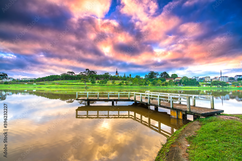 Fototapeta premium Dawn on love bridge overlooking the lake with the dramatic sky welcomes new day in the tourist city of Vietnam
