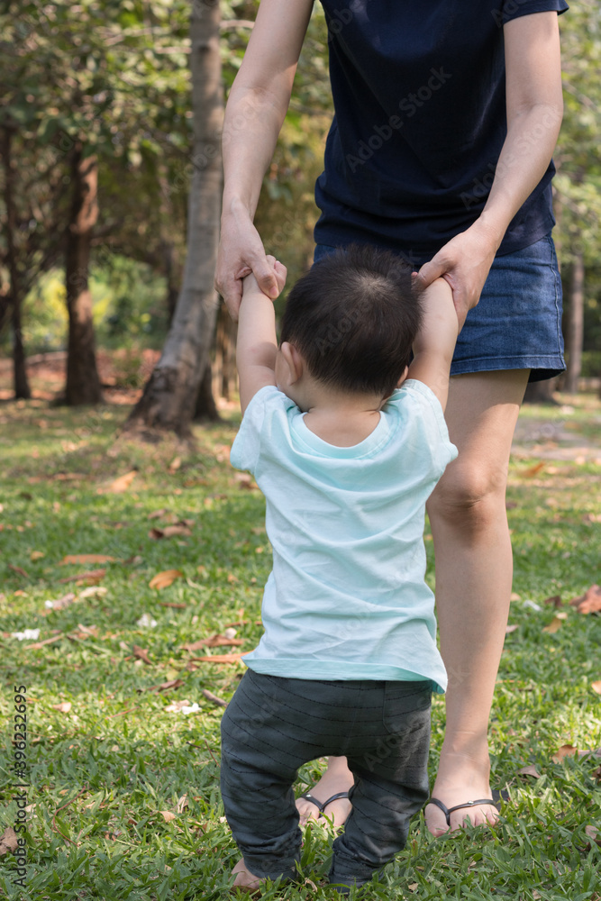 Mother holding hands of her son making first steps. Mother holding hands of her son making first steps.