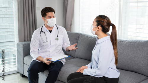 Asian female Patient listening intently to a male doctor explaining symptoms about health complaints in her home, health care concept