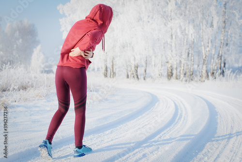 Fitness woman runner on sunny winter road.