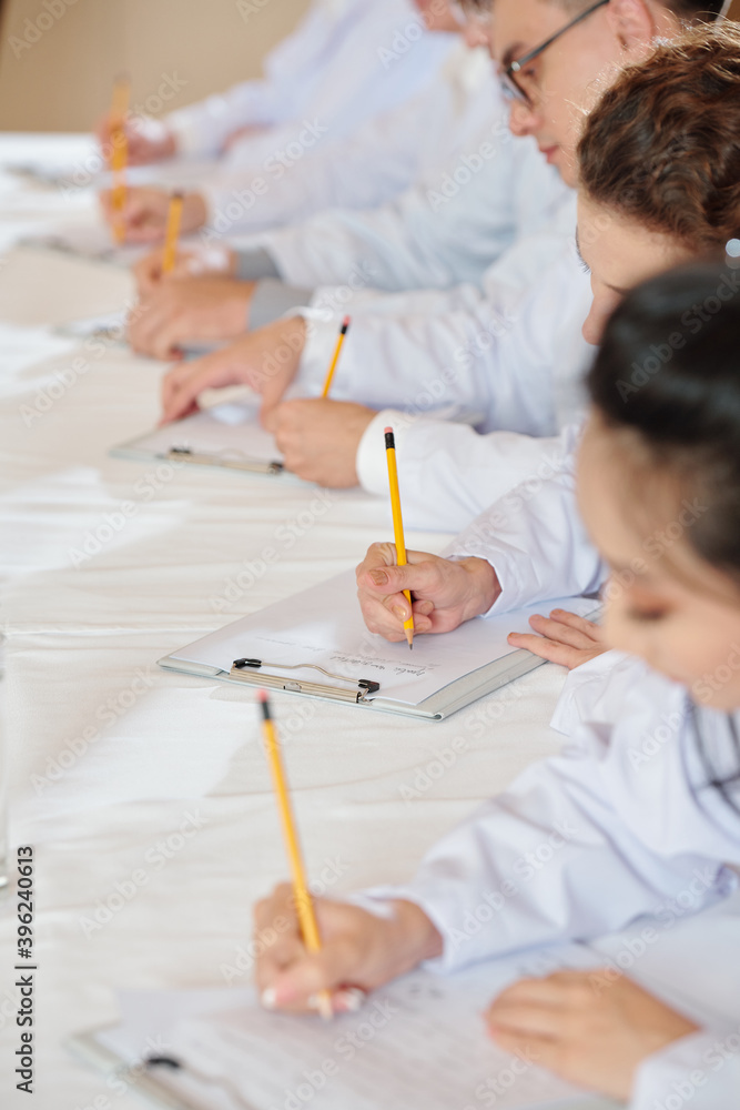 Students attending lesson in medical school and taking notes in notebooks Students attending lesson in medical school and taking notes in notebooks