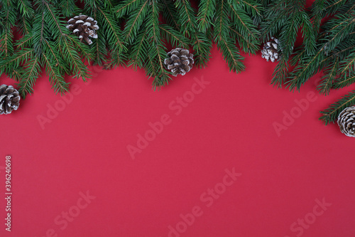 fir branches and cones on red background   top view flat lay copy space. Christmas and New Year background