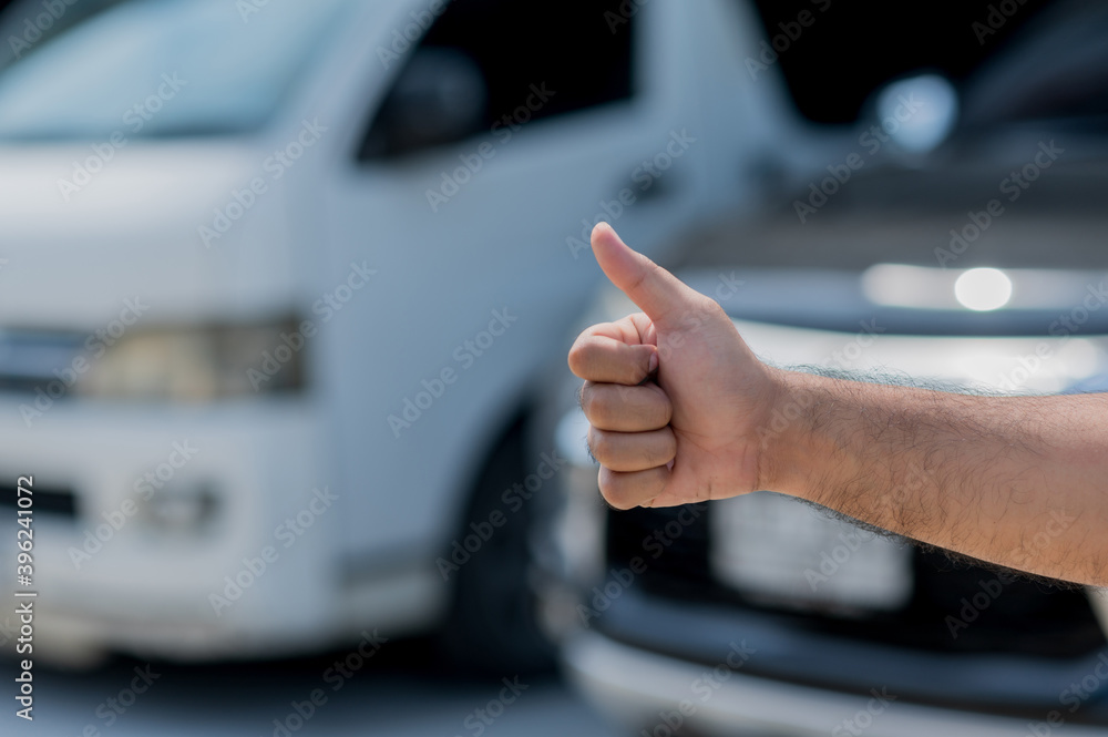 Male hand showing thumbs up on the car service background. Good car maintenance service concept.