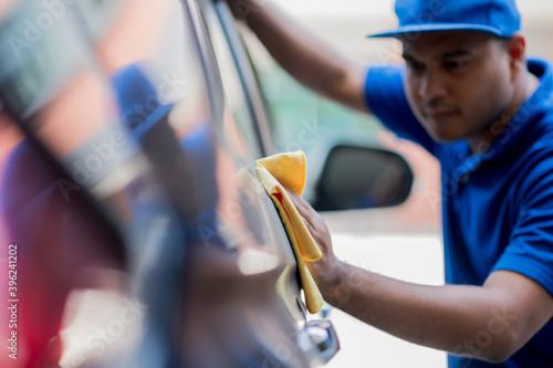 Fototapete The asian staff polishes the car, uses a microfiber cloth and polish to wipe the car's body with polish