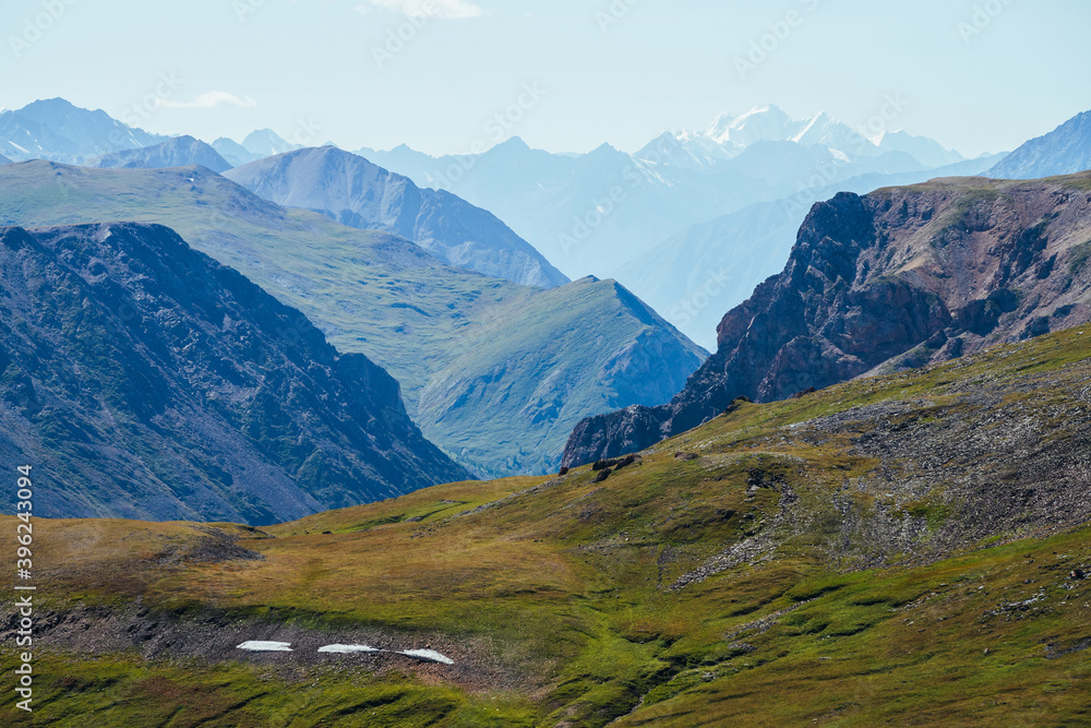 Awesome alpine landscape with great snowy mountain behind rocky mountains and deep gorge. Giant rockies and deep abyss. Wonderful highland scenery with huge glacier and big rocks and precipice.