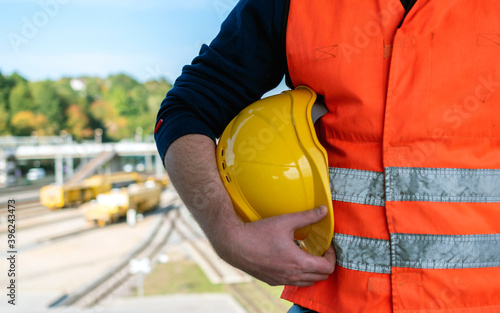 Railroad worker hold yellow helmet at the sunny day