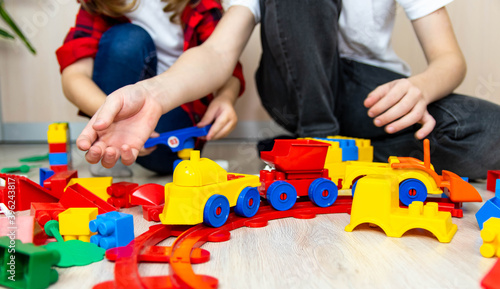 Girl and boy play at home constructor on the floor. Children build from colored blocks.