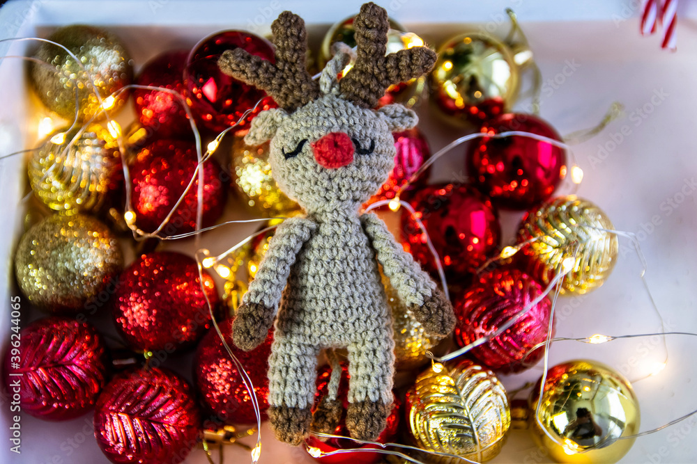Handmade crocheted deer on the background of Christmas balls and garland lights. Handmade crocheted deer on the background of Christmas balls and garland lights.